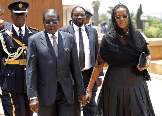 Zimbabwe's President Robert Mugabe and his wife Grace hold hands as they walk away after paying their respects at the coffin of former South African President Nelson Mandela, which is lying in state, at the Union Buildings in Pretoria